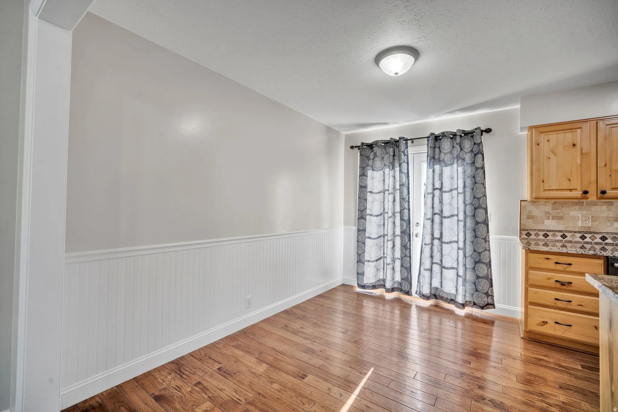 Hardwood-finish flooring complementing white wainscoting and light-toned walls