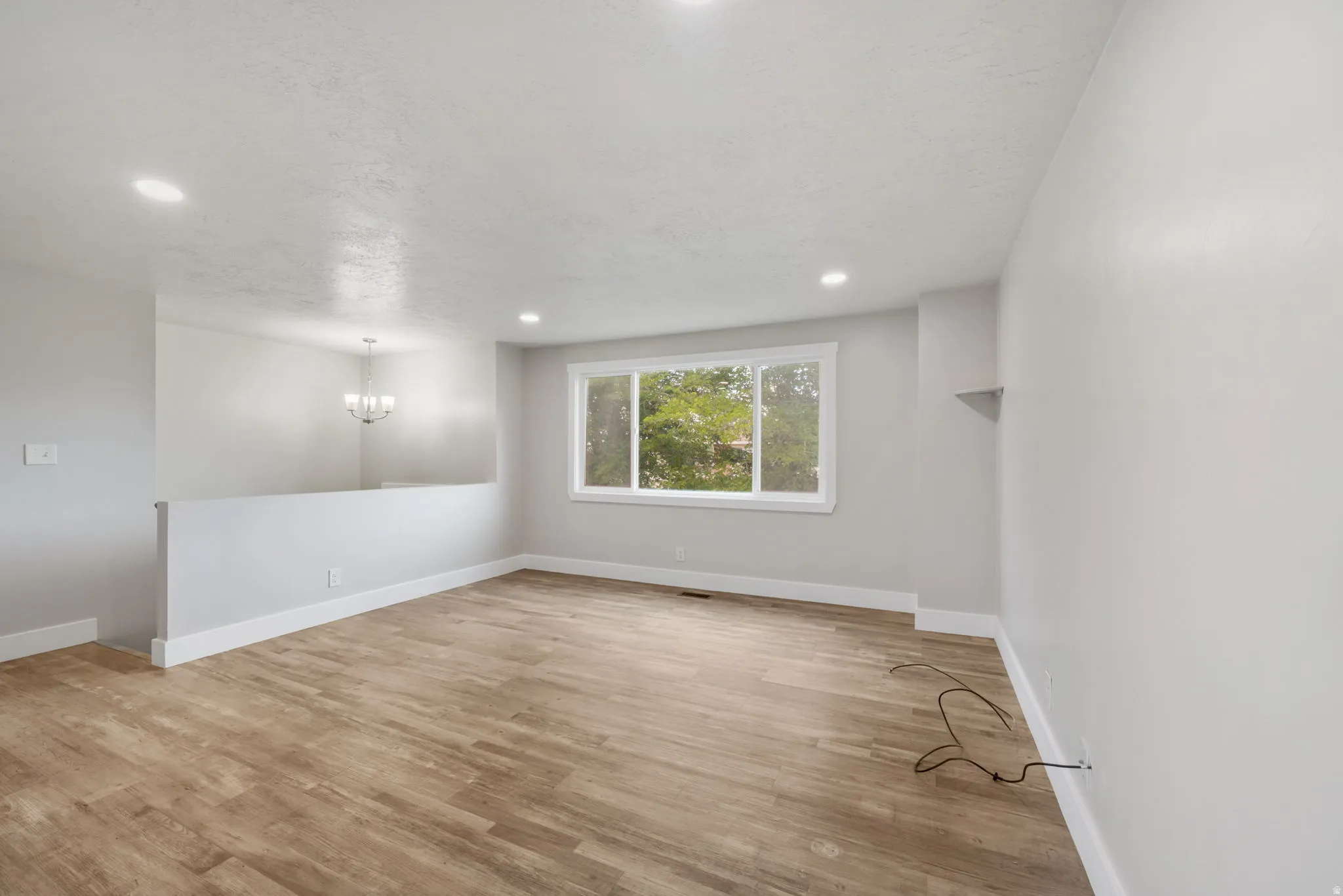 Spacious room featuring wood-finish flooring, recessed lighting, and a large window