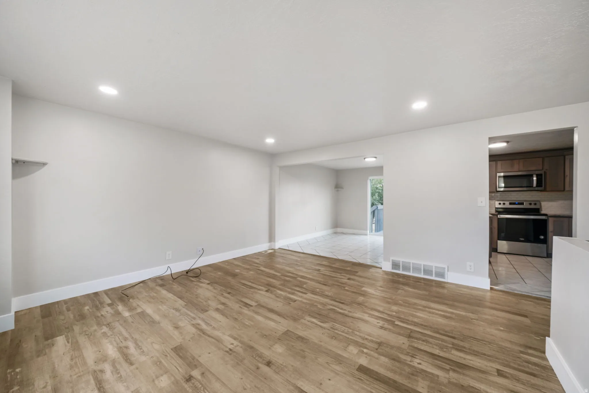 Spacious living area featuring wood-finish flooring, recessed lighting, and white baseboards