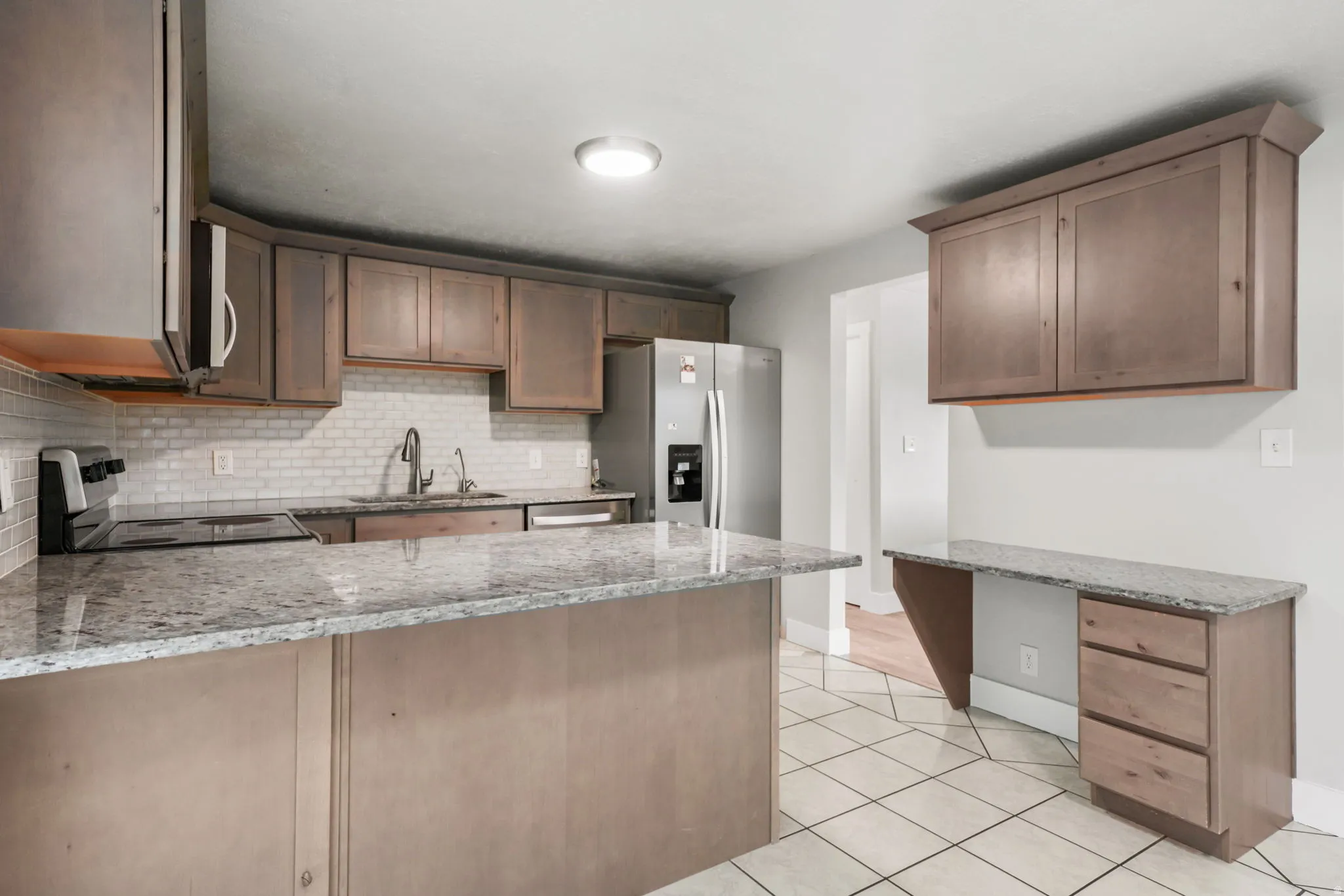 Kitchen featuring light wood-finish cabinetry, stainless steel appliances, and a mosaic tile backsplash
