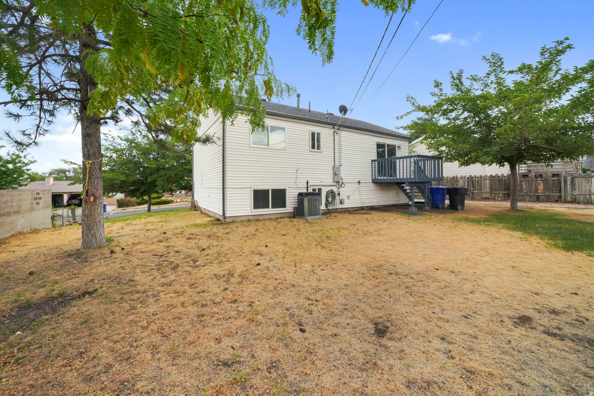 Rear exterior with white siding, showcasing a multi-level wood deck with steps, and an air conditioning unit