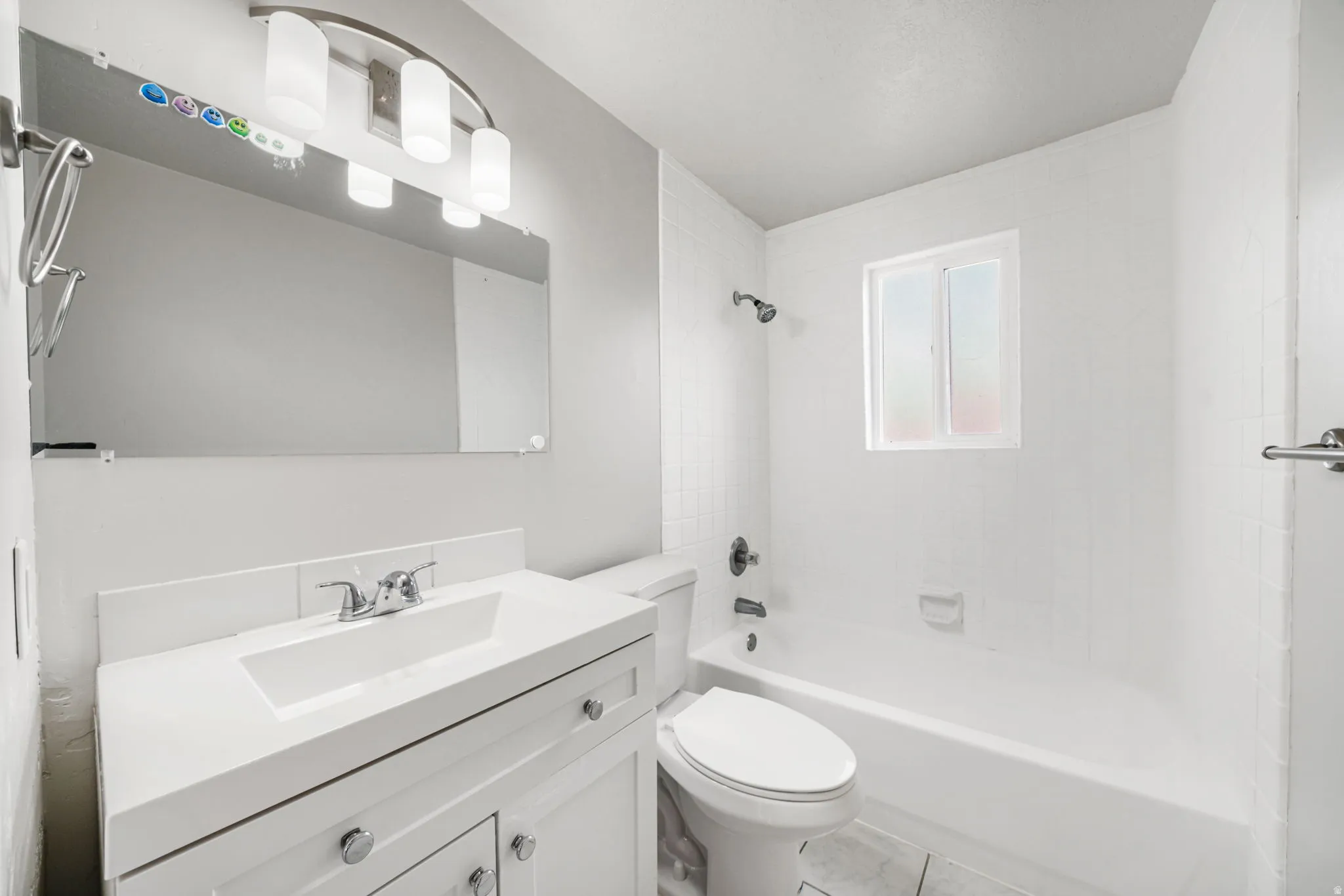 Modern bathroom featuring a white vanity with integrated sink, chrome faucet, and a large mirrored wall