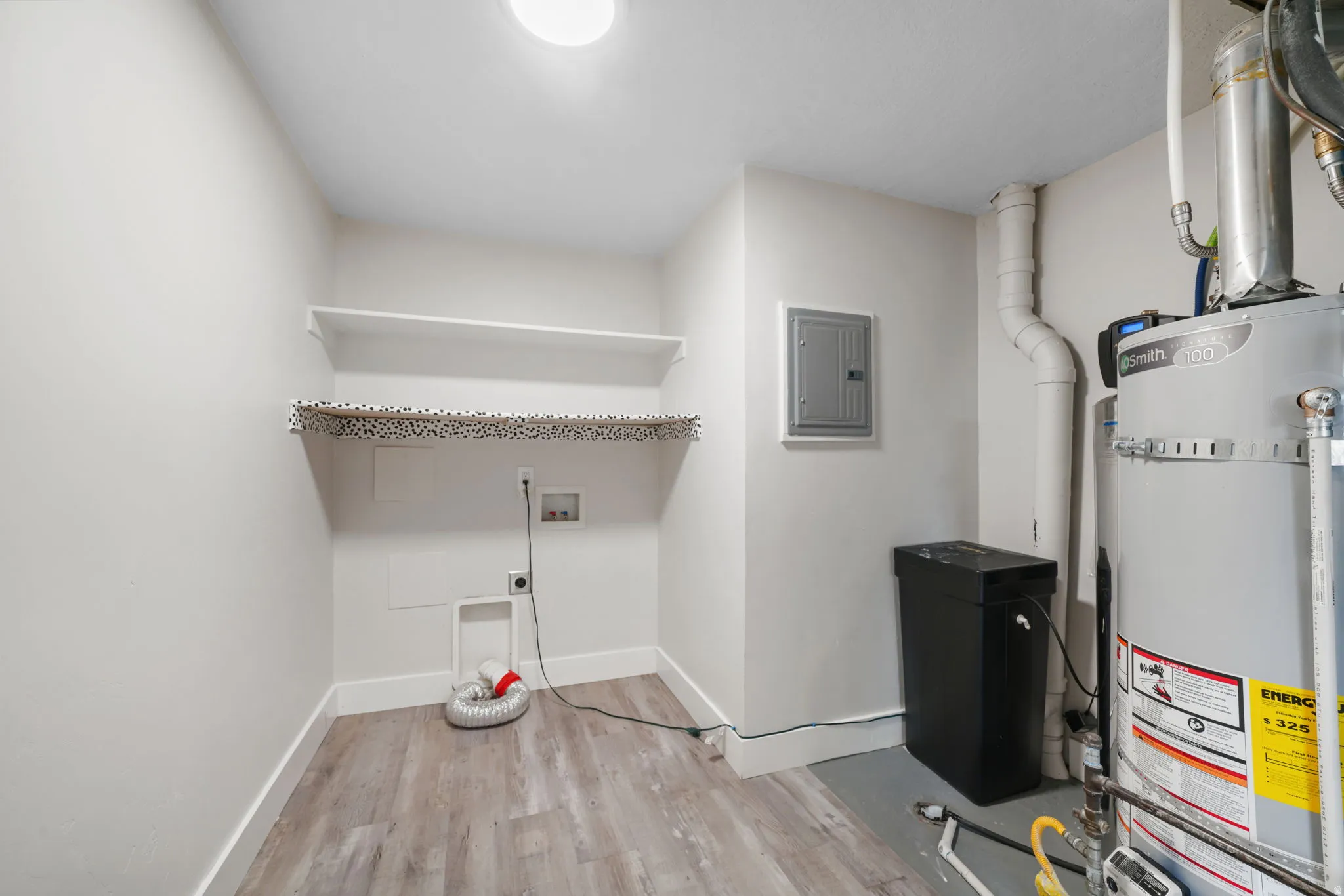 Dedicated utility space featuring wood-finish flooring, white walls, and an overhead light fixture