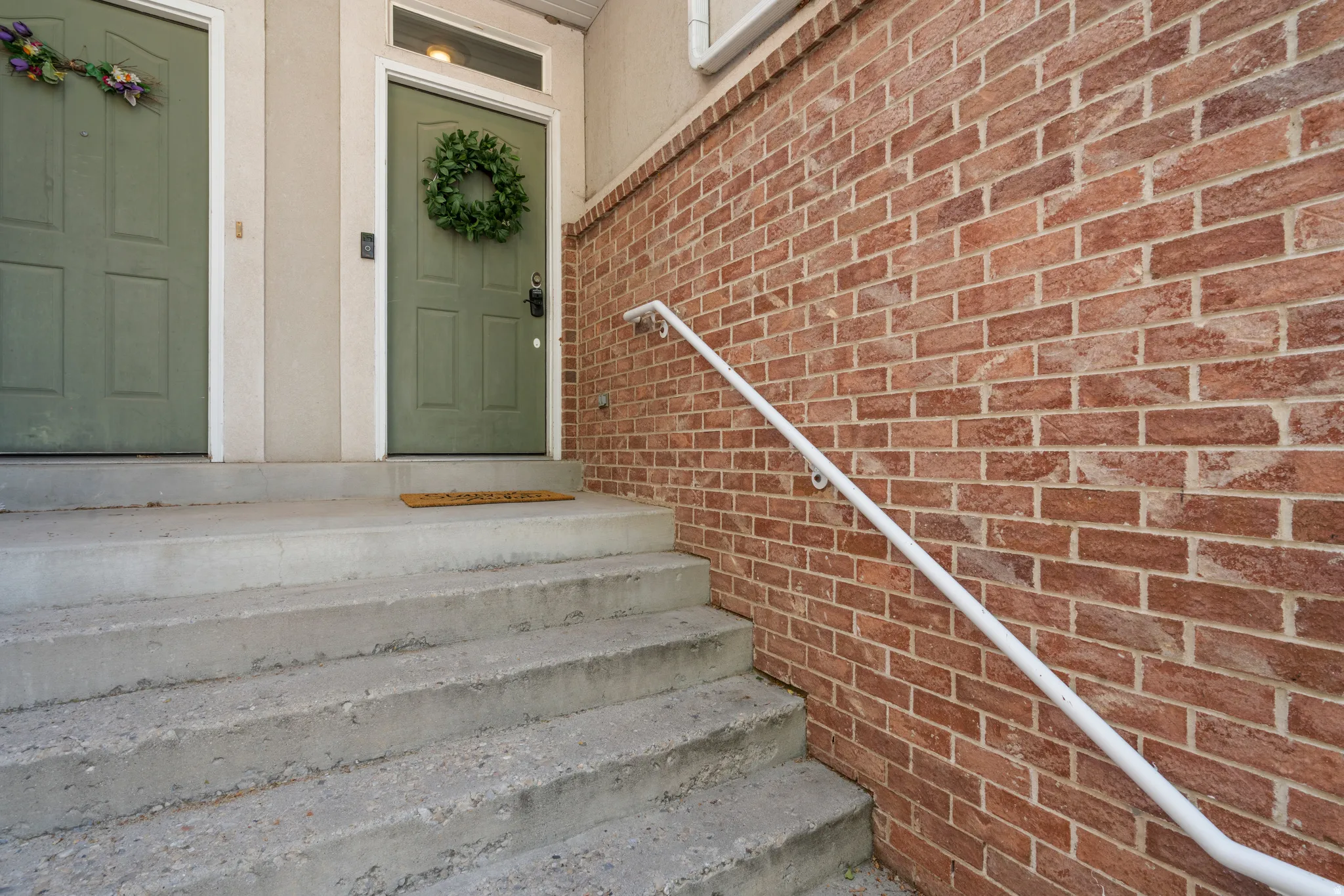 Brick exterior facade featuring concrete steps with a white handrail