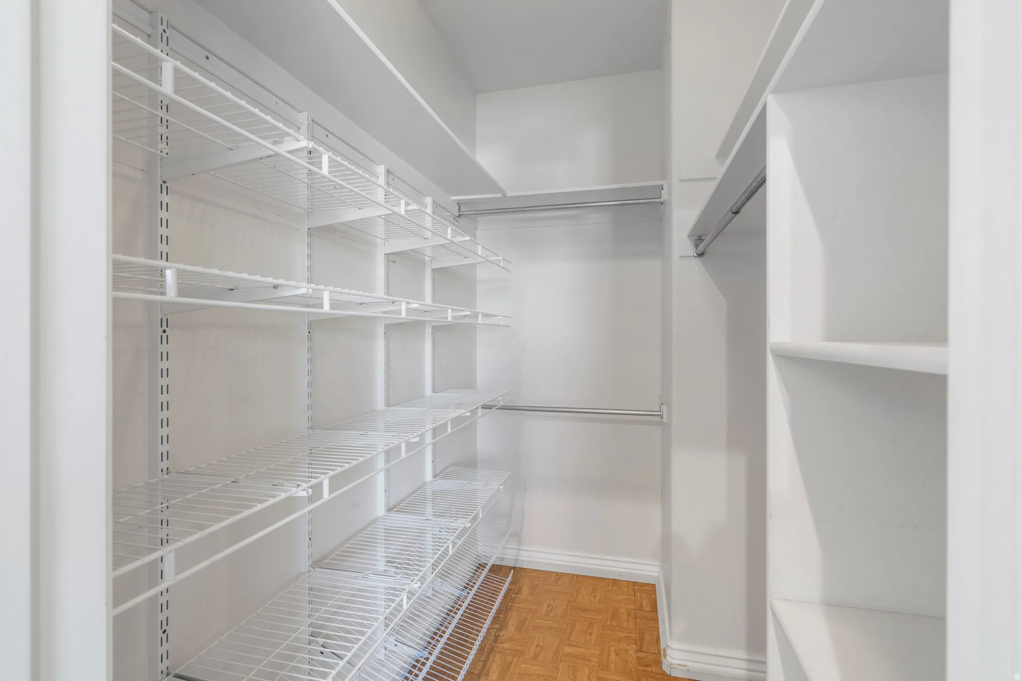 Walk-in closet featuring wire shelving, built-in wooden shelving, and multiple hanging rods