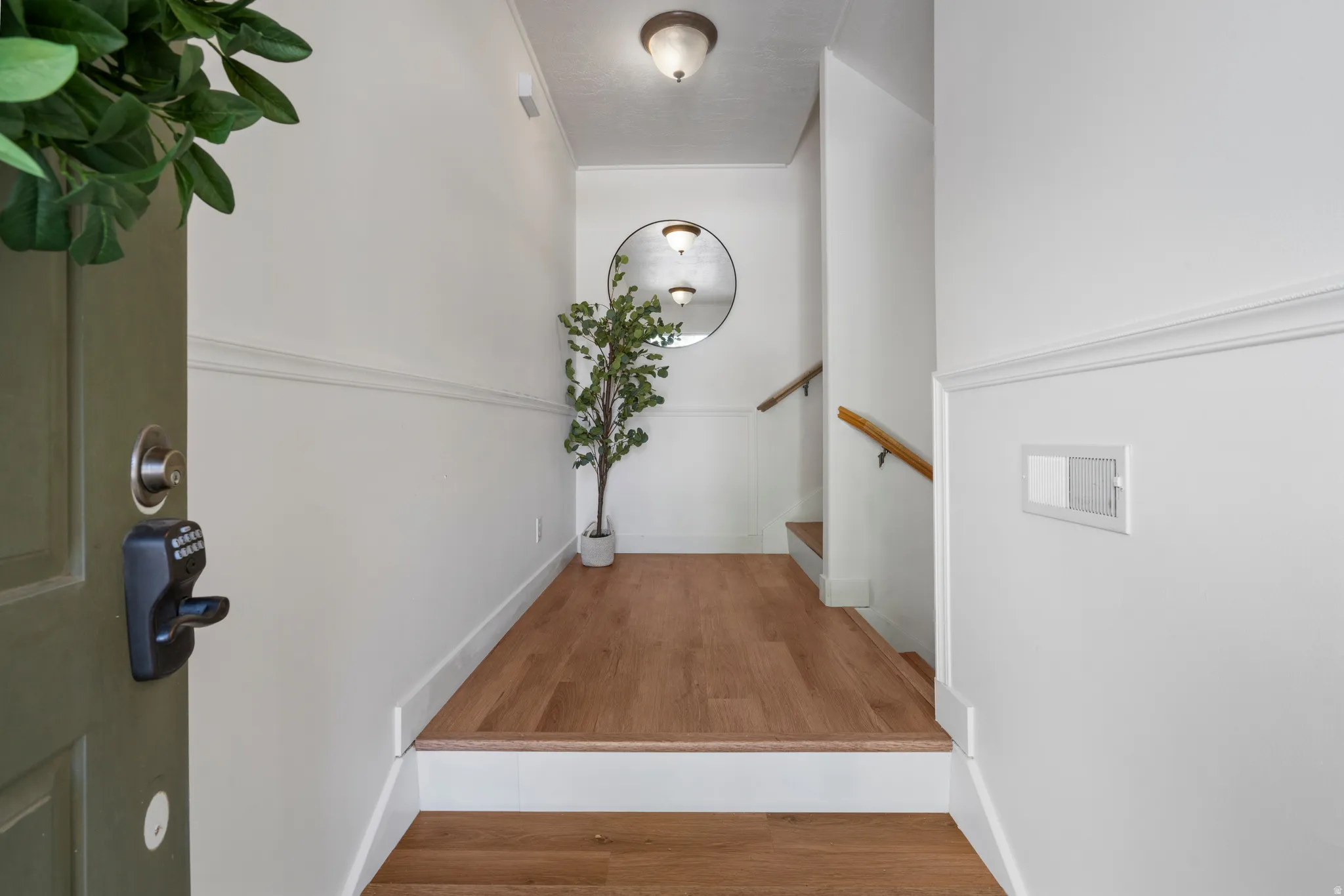 Entryway featuring wood-finish flooring, white wainscoting, and a neutral wall color