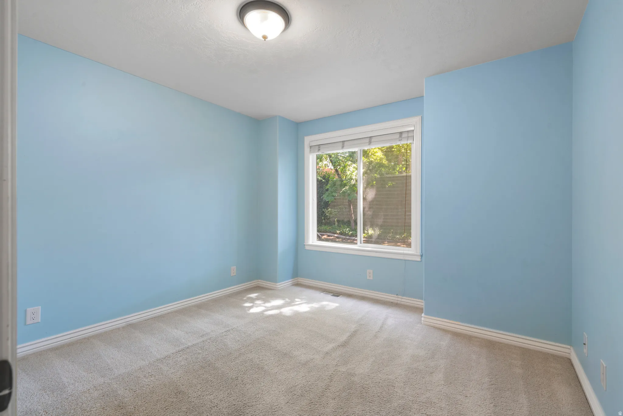 Room featuring light blue wall paint, light-colored carpet flooring, and white baseboards