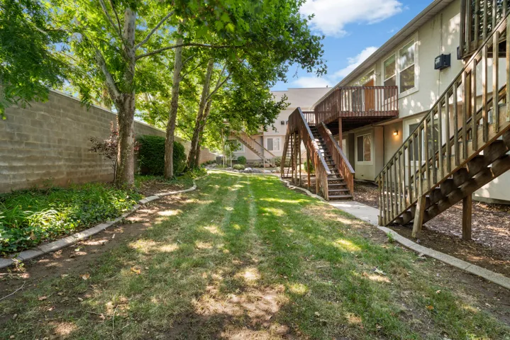 Expansive grass lawn featuring mature trees and a block privacy wall