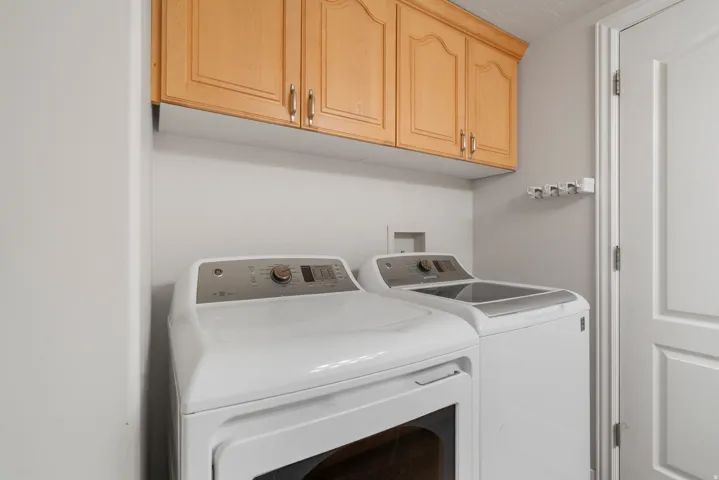 Utility area featuring light wood-finish cabinetry, white walls, and a paneled door