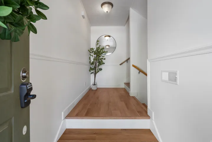 Entryway featuring wood-finish flooring, white wainscoting, and a neutral wall color