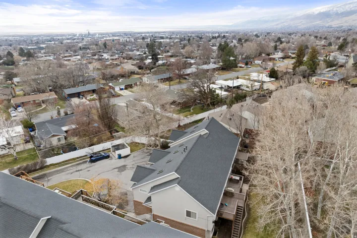 Townhome property featuring a multi-level deck, dark shingle roof, and light-colored siding with brick accents