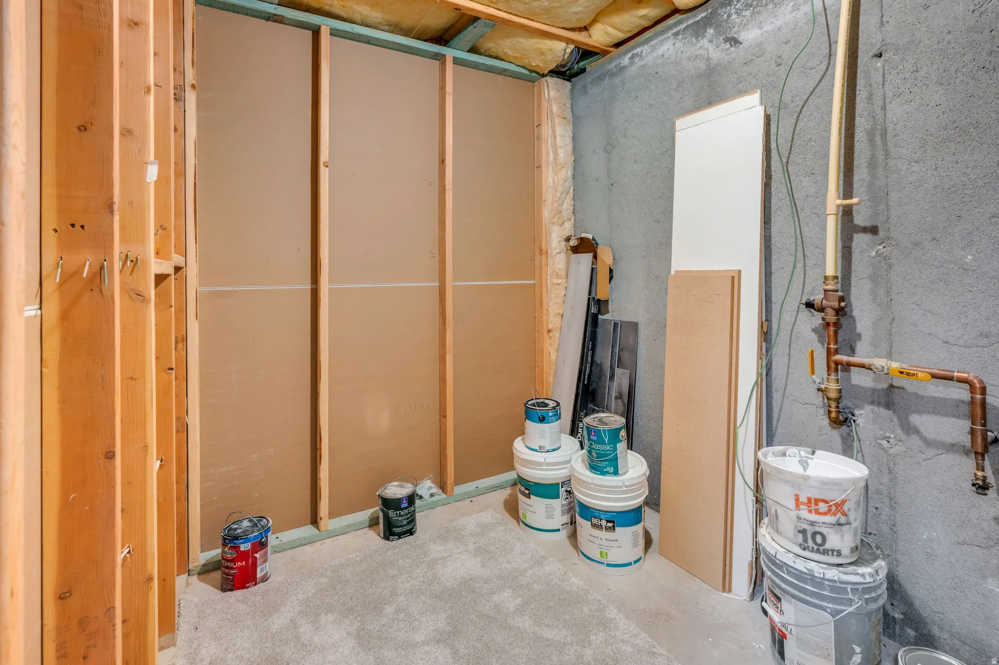 Basement area featuring unfinished wood framing, partially installed wallboard, and exposed concrete walls
