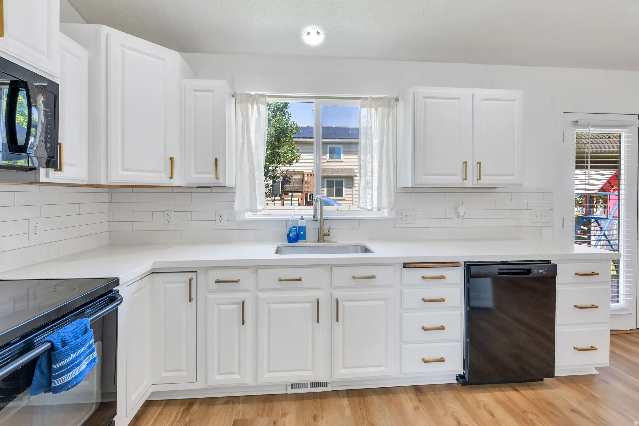 Kitchen featuring white cabinetry, light countertops, subway tile backsplash, and a built-in dishwasher