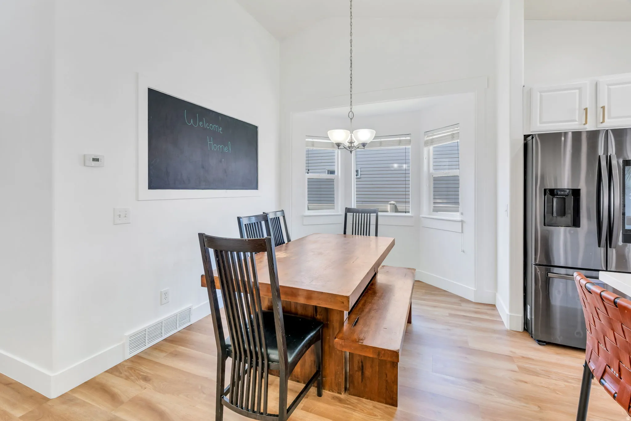 Dining area featuring wood-finish flooring, vaulted ceilings, and a bay window