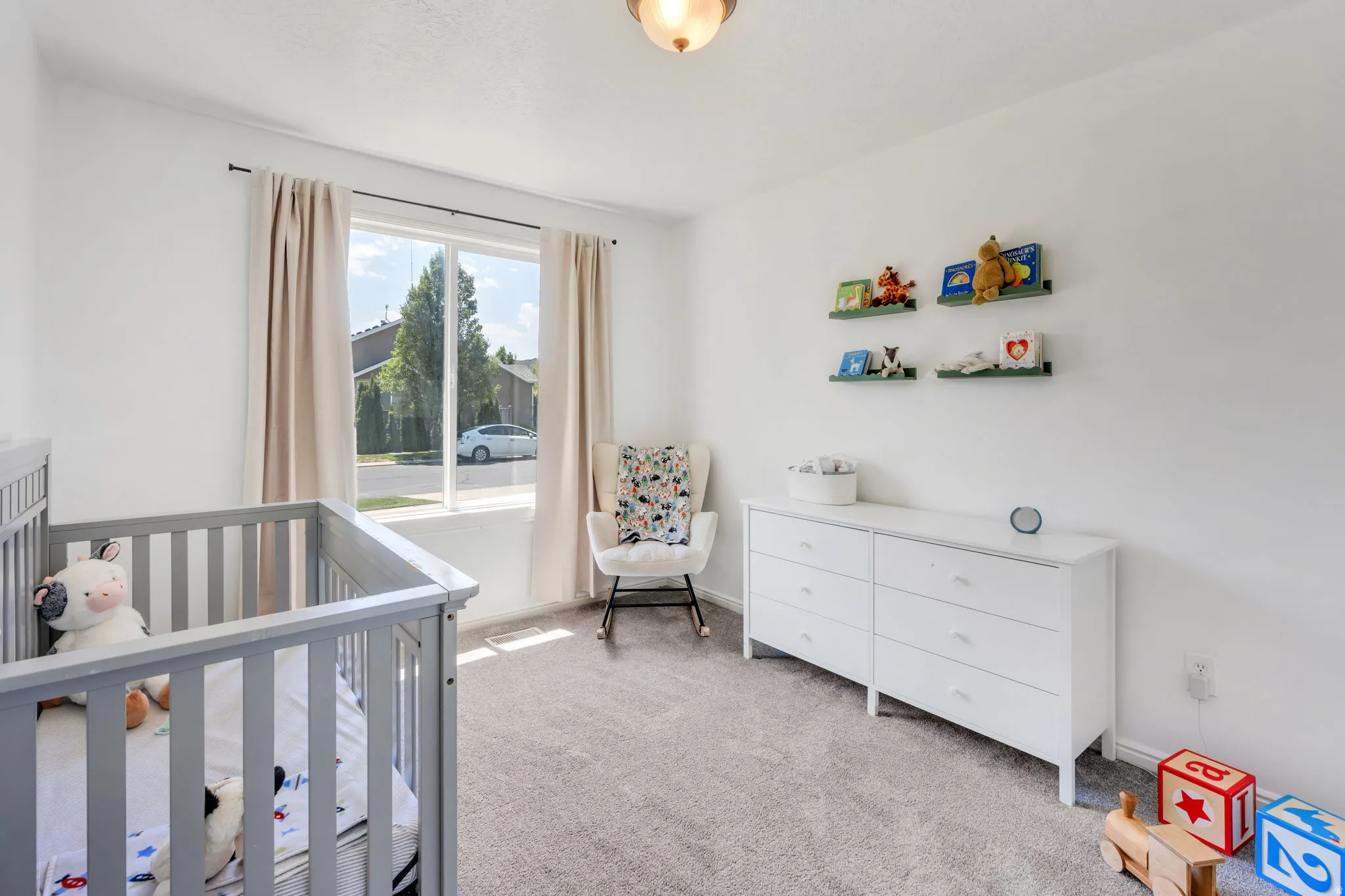Bright room featuring a large window with natural light, neutral wall colors, and carpeted flooring