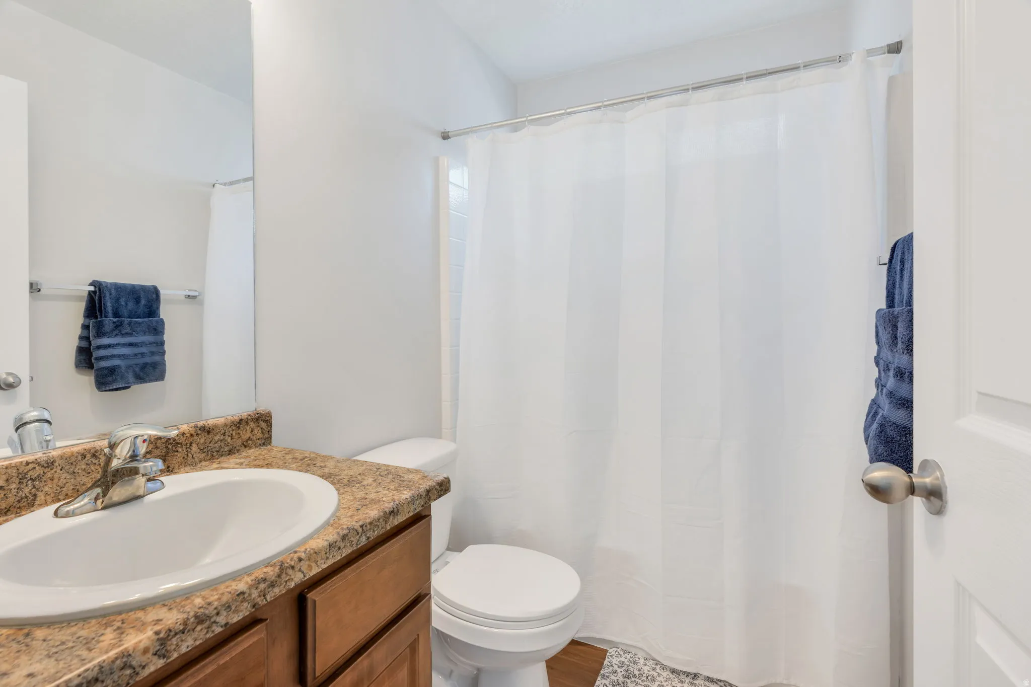 Bathroom featuring a vanity with a white basin, speckled countertop, and wood-finish cabinetry