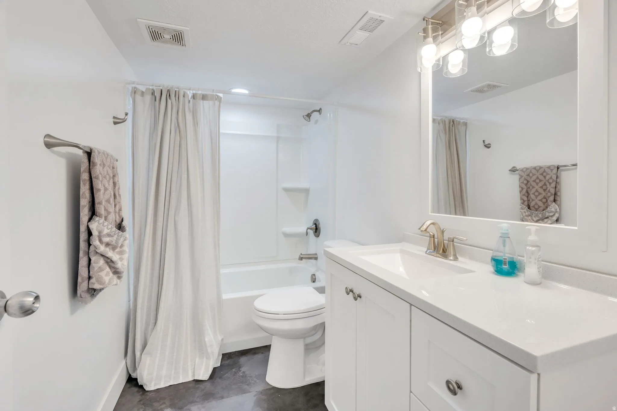 Bathroom featuring a white vanity with integrated sink, brushed nickel faucet, and white framed mirror