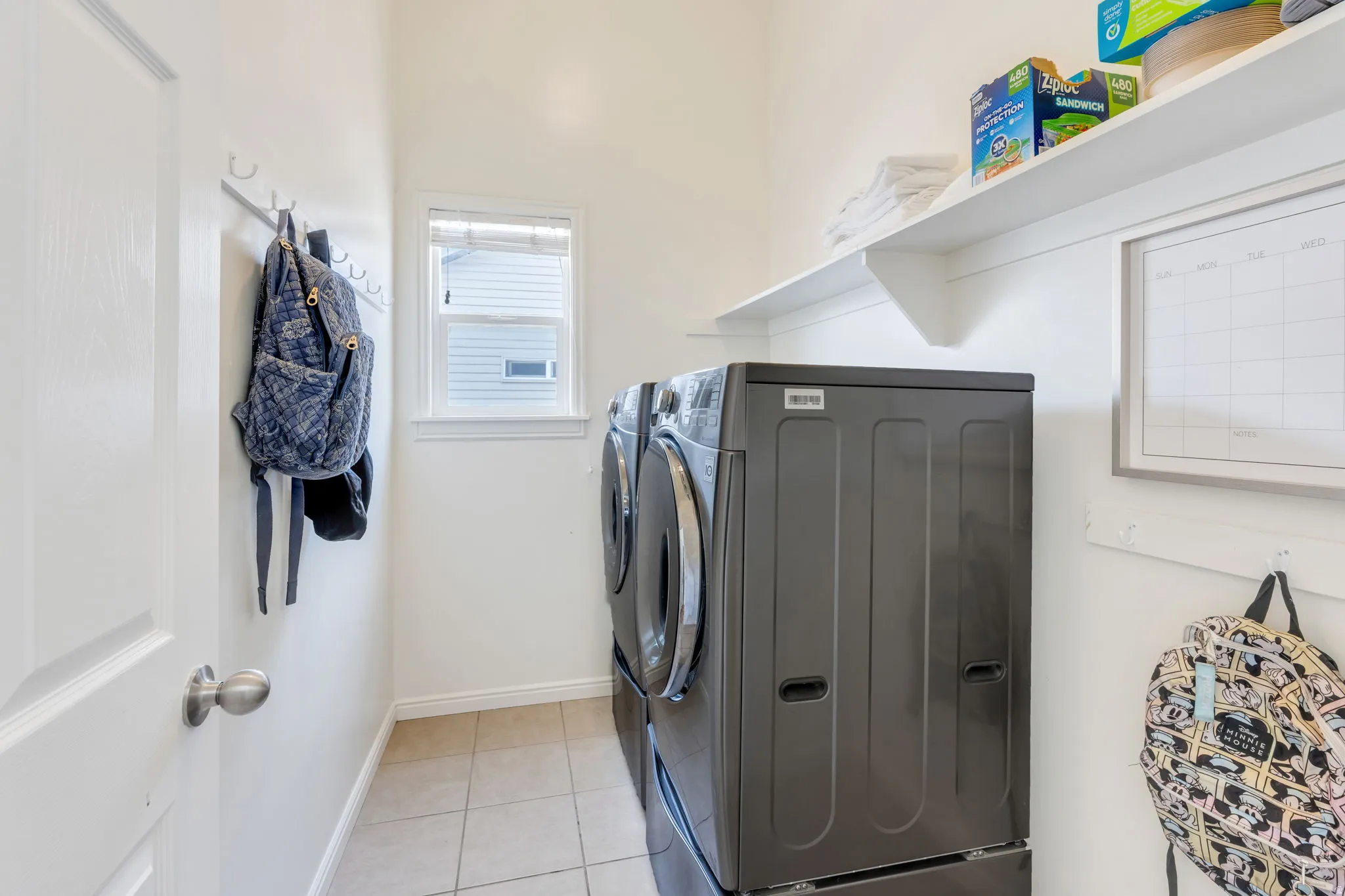Dedicated utility space featuring a window, tile flooring, and integrated shelving