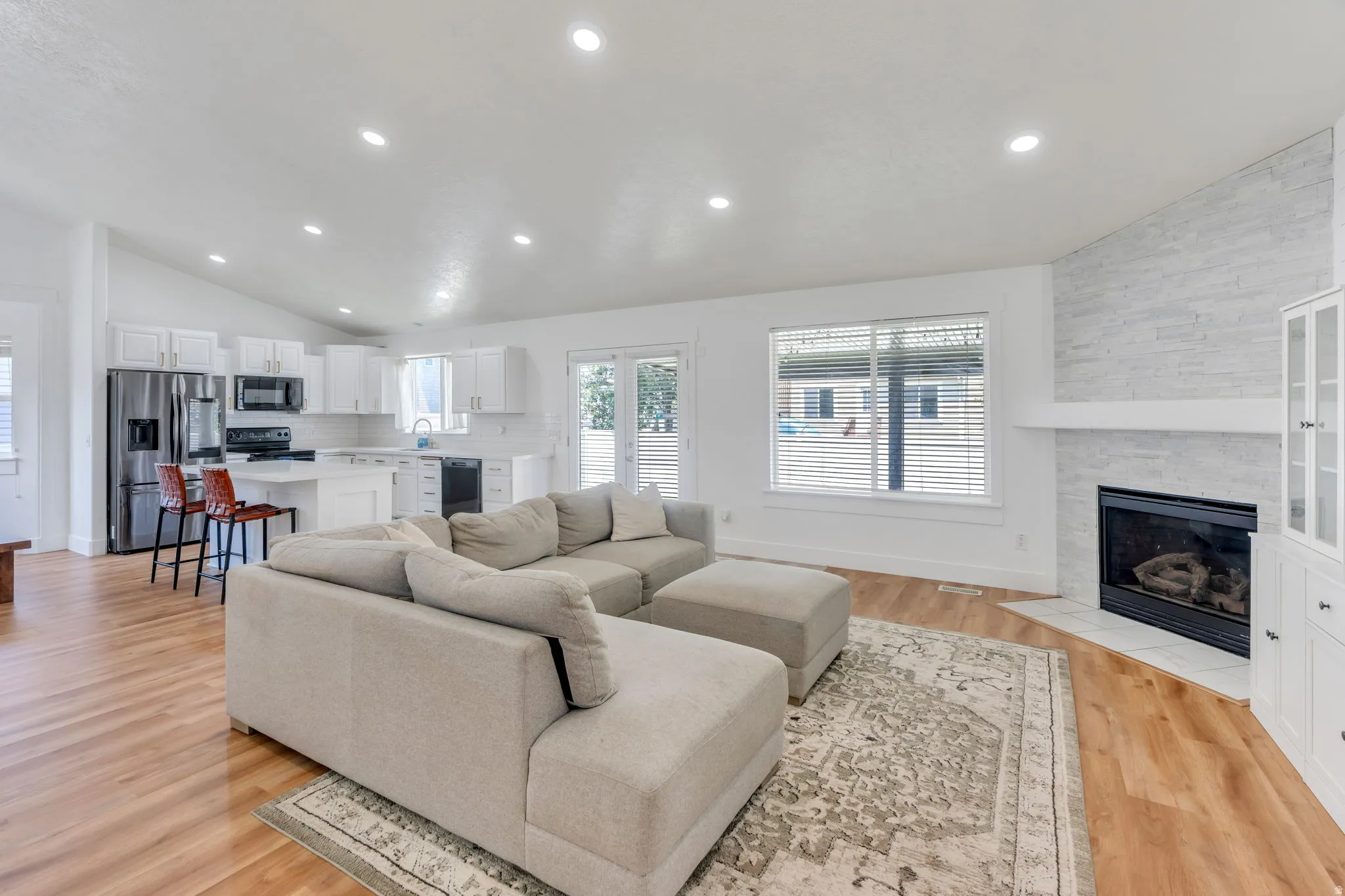 Open-concept living area featuring a spacious sectional seating arrangement, recessed ceiling lighting, and hardwood flooring throughout