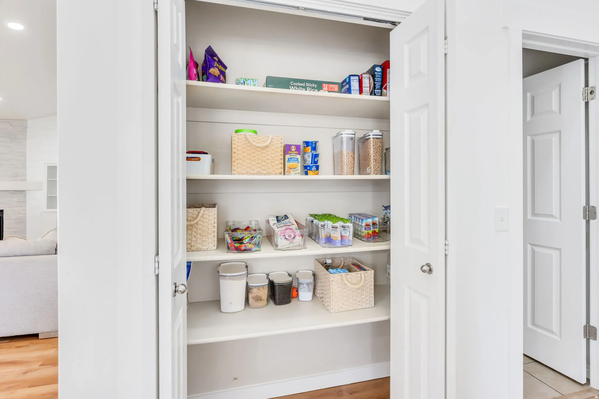 Spacious pantry featuring multiple white shelving units and bi-fold doors