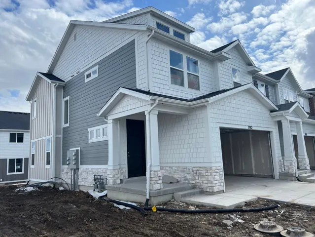 Modern townhome exterior featuring multi-toned siding, white shake shingles, and stone veneer accents