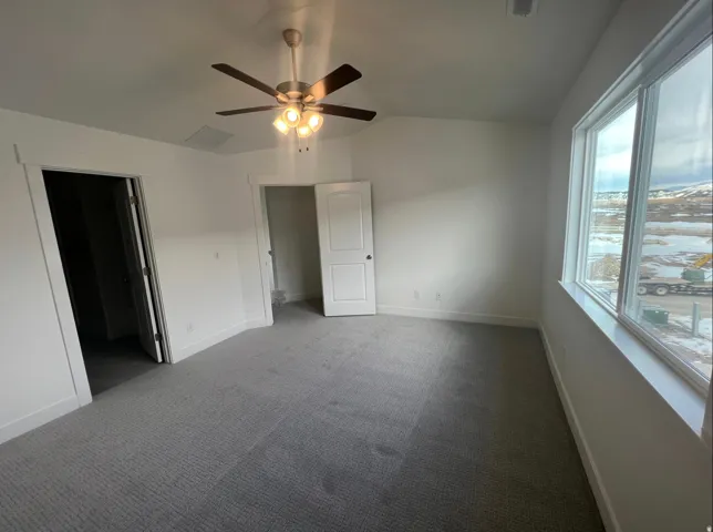 Spacious room featuring light gray carpet, white walls, and a multi-pane window with white trim