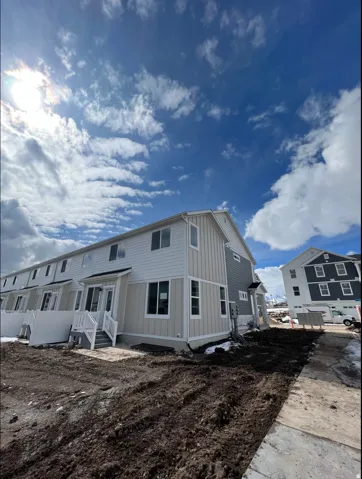 Contemporary townhome featuring a multi-story design with a light-colored siding and dark trim accents