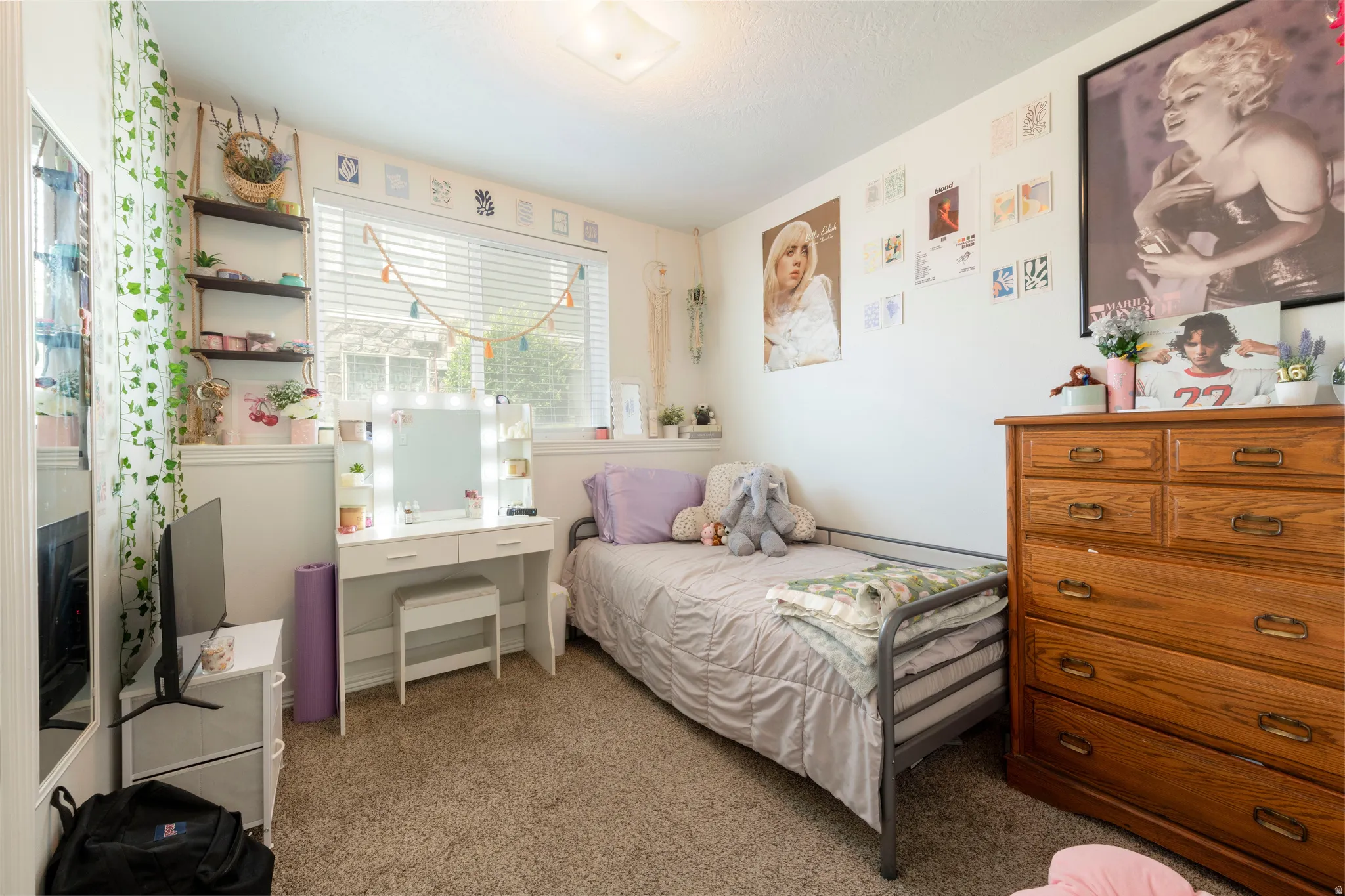 Carpeted room featuring a single window with blinds, built-in shelving, white baseboards, and a ceiling-mounted light fixture