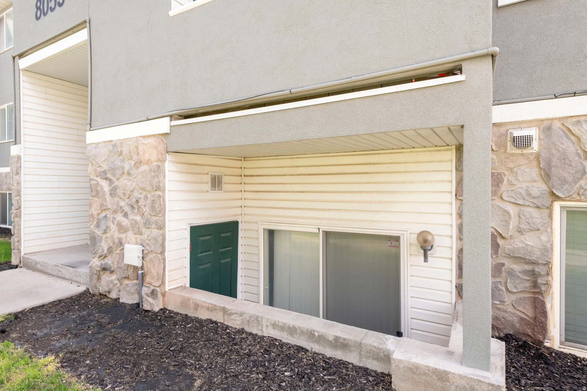 Exterior building features include a stucco finish and stone veneer accents