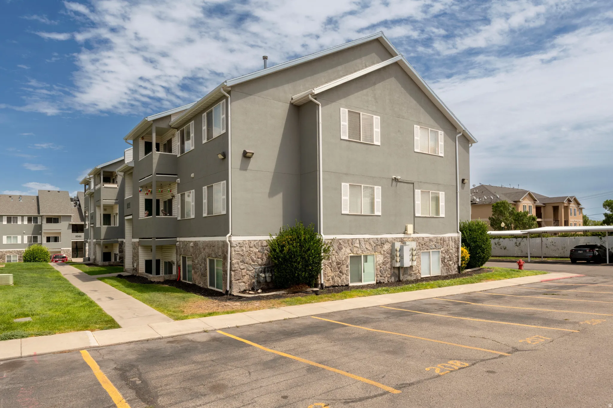 Multi-story building featuring a gray stucco exterior with a stone veneer foundation