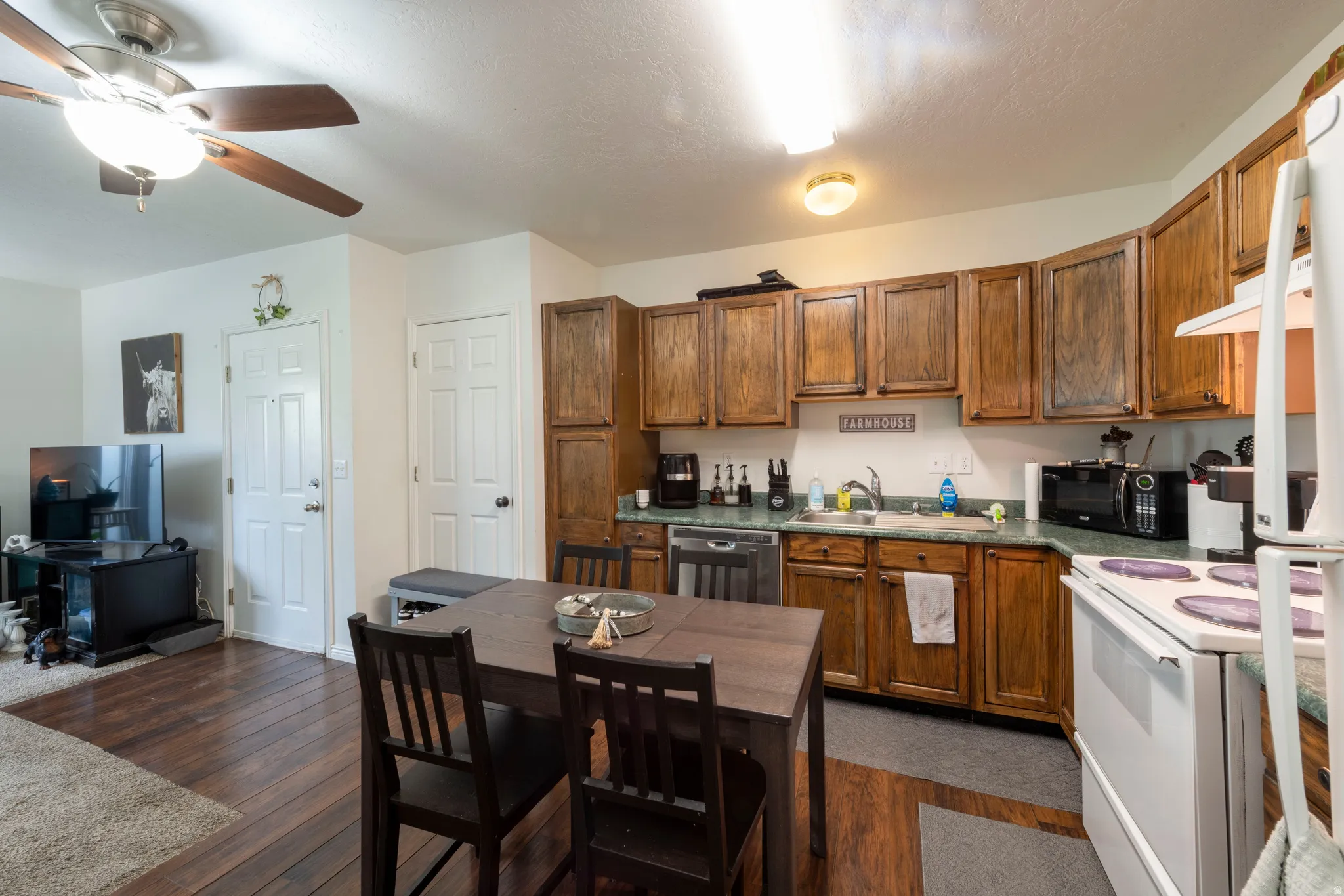 Kitchen area featuring wood-finish cabinetry, a white electric range, and a built-in dishwasher