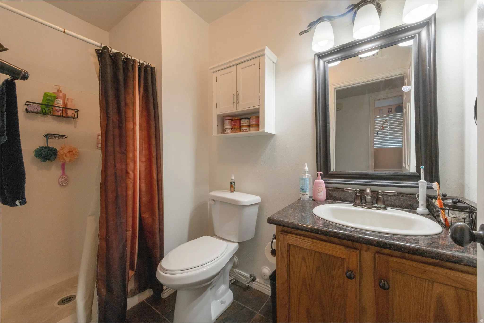 Bathroom featuring a wood-finish vanity with a dark countertop and integrated sink