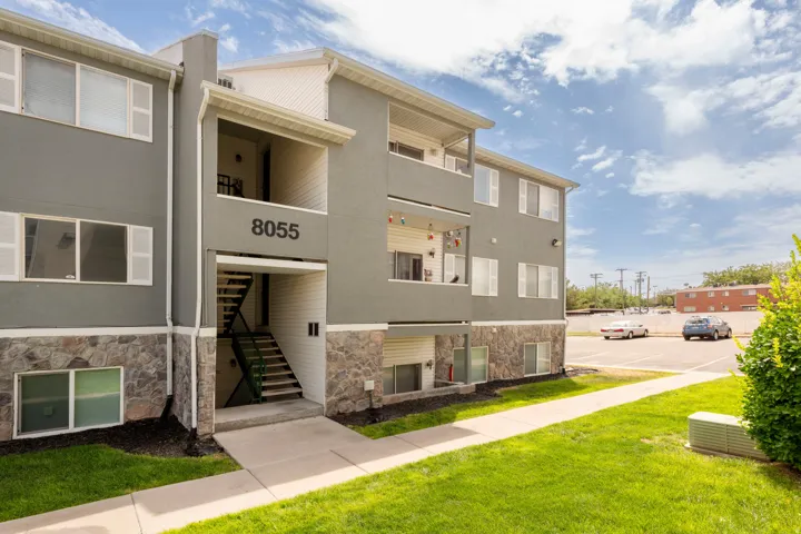 Multi-story apartment building with a gray stucco exterior and stone veneer accents