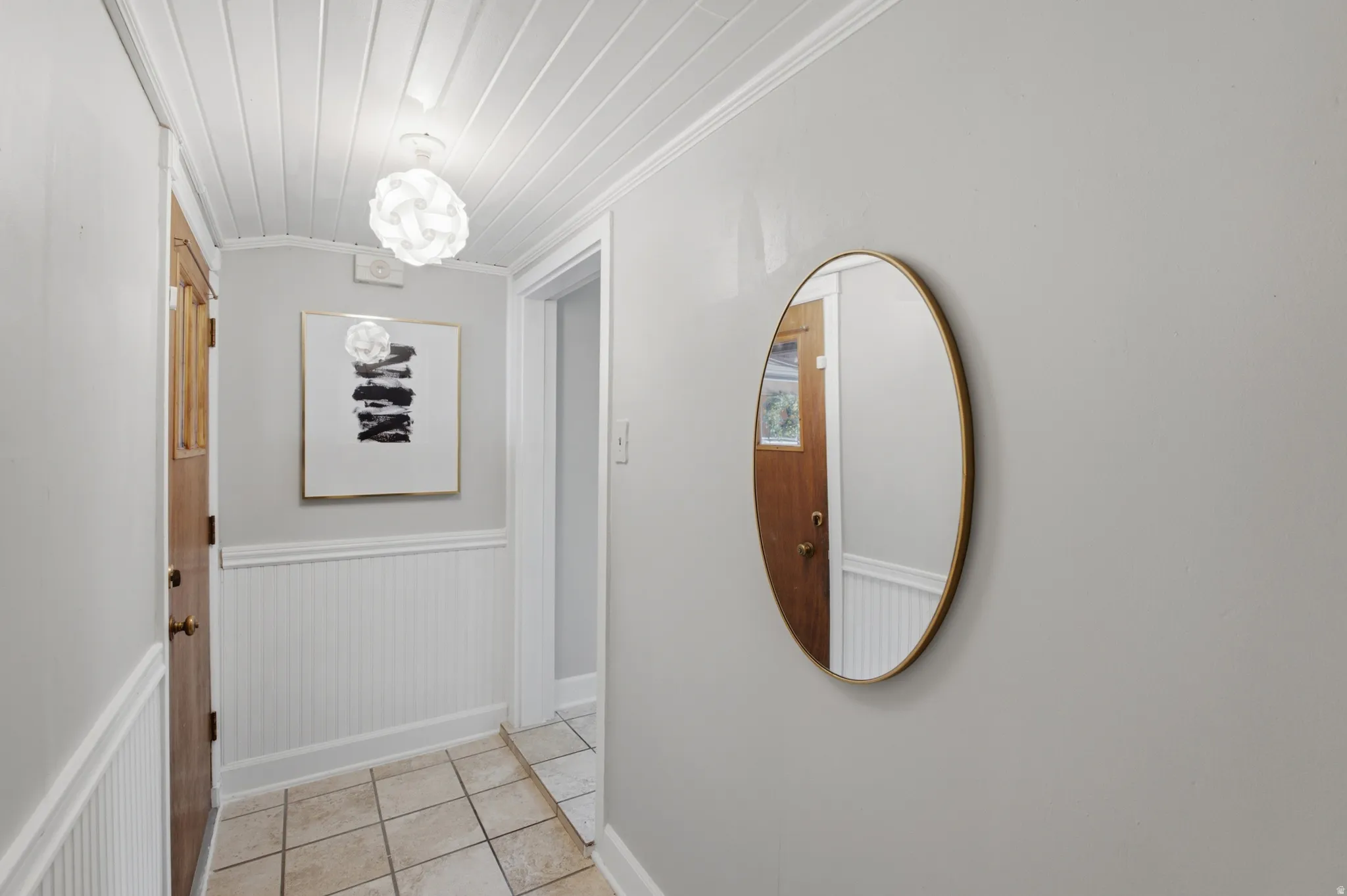 Entryway featuring tile flooring, white wainscoting, and a white plank ceiling