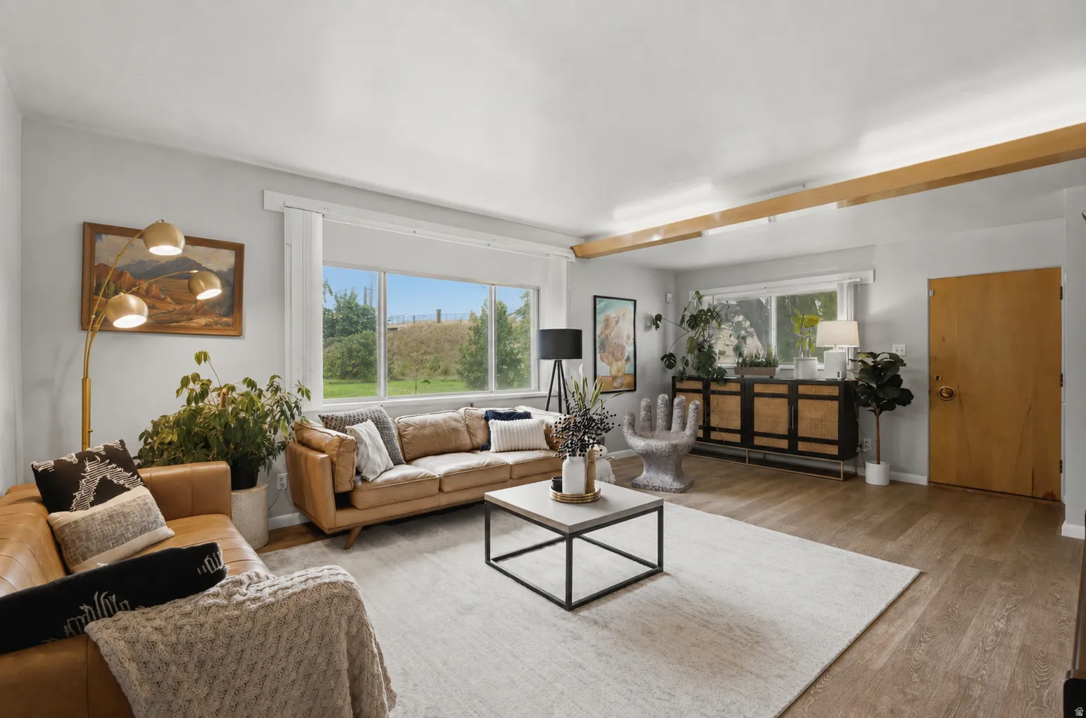 Spacious living area featuring beautiful vinyl wood flooring and a large front-facing window.