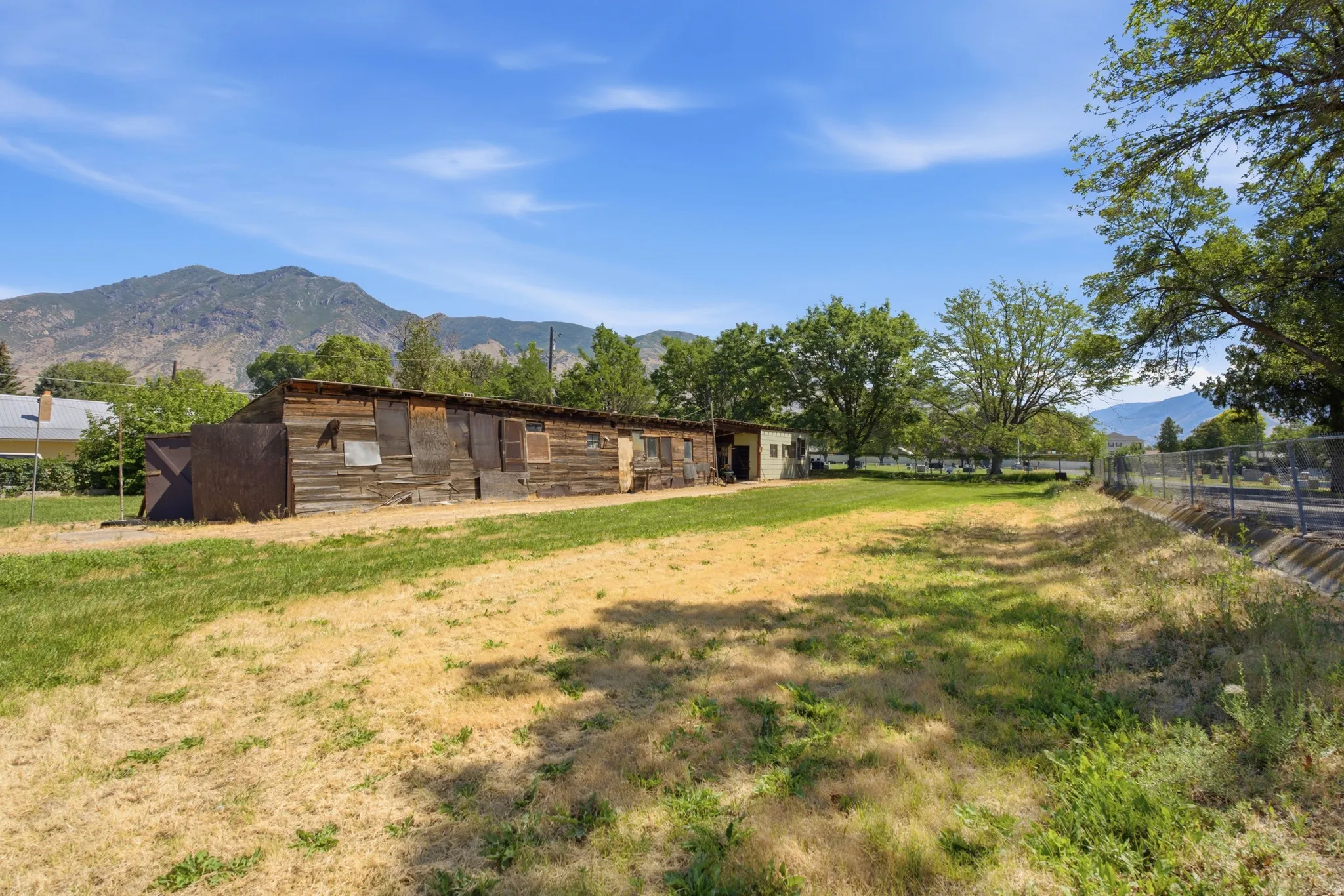 Expansive grassy lot with mature trees and mountain scenery