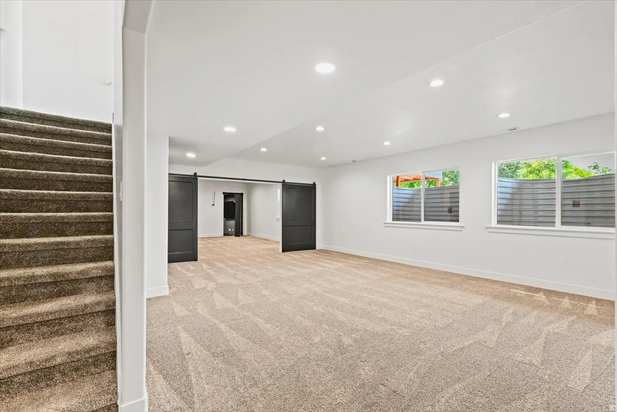 Spacious open floor plan with plush carpet flooring, recessed ceiling lighting, and abundant natural light from multiple windows
