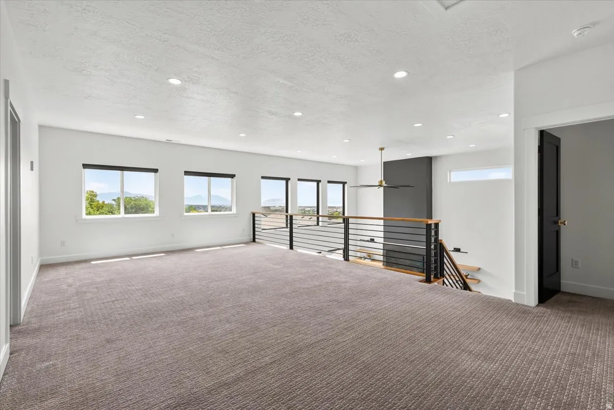 Spacious upper-level area featuring plush patterned carpeting and recessed lighting
