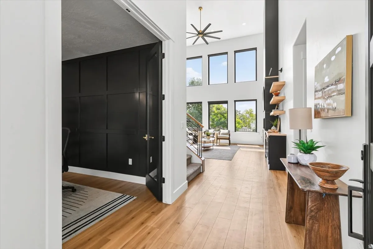 Foyer with wood-finish flooring, a double-height ceiling, and a contemporary ceiling fan