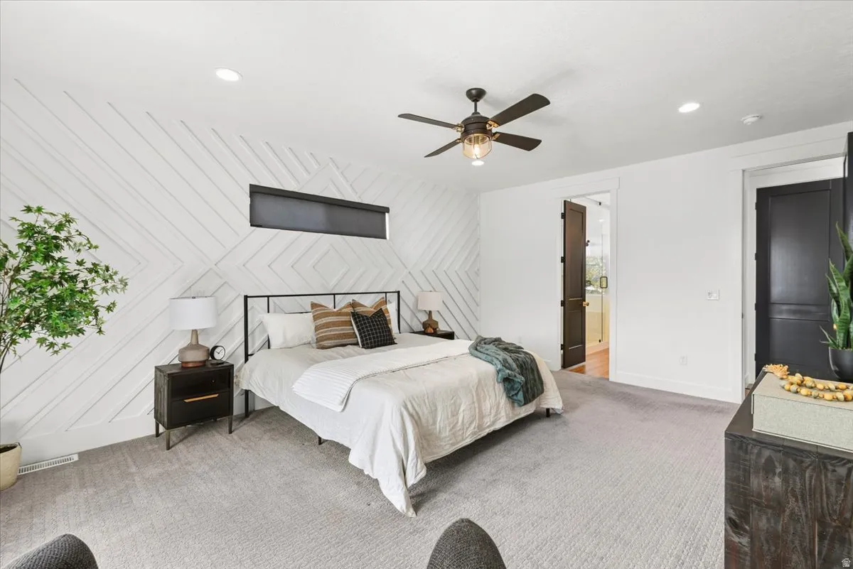 Master bedroom featuring a shiplap accent wall with geometric pattern, metal-frame bed, ceiling fan with integrated lighting, recessed ceiling lights, and plush carpeting throughout