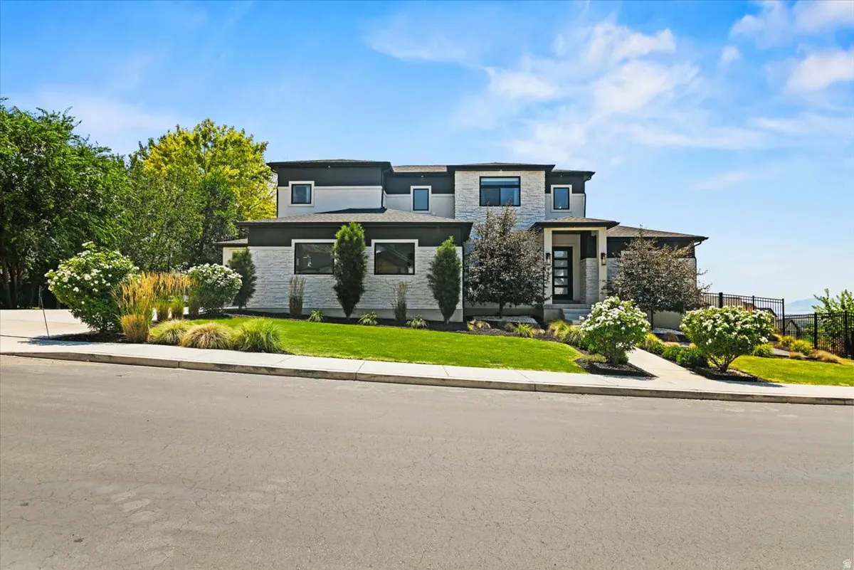 Modern exterior featuring light-colored stone accents, dark trim, and a prominent front entry with a dark-framed glass door