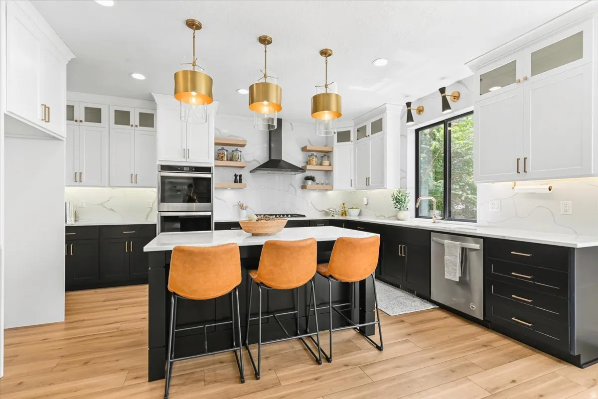 Contemporary kitchen featuring a large central island, white countertops, and wood-finish flooring