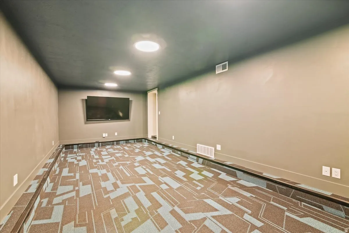 Spacious recreational room featuring geometric wood-finish flooring in warm brown and tan tones, recessed ceiling lighting, and neutral wall finishes