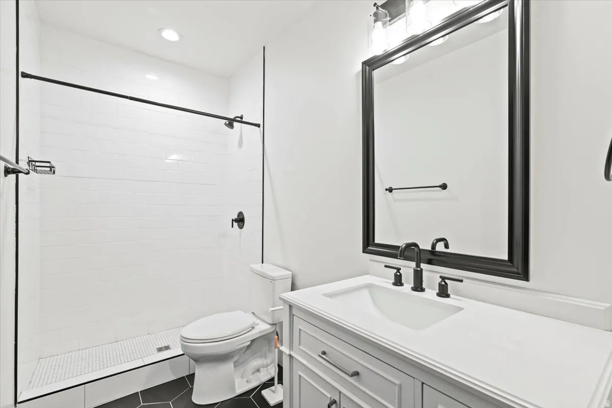 Modern bathroom featuring a white subway tile shower, clear glass enclosure, matte black fixtures, and a white vanity with a rectangular sink