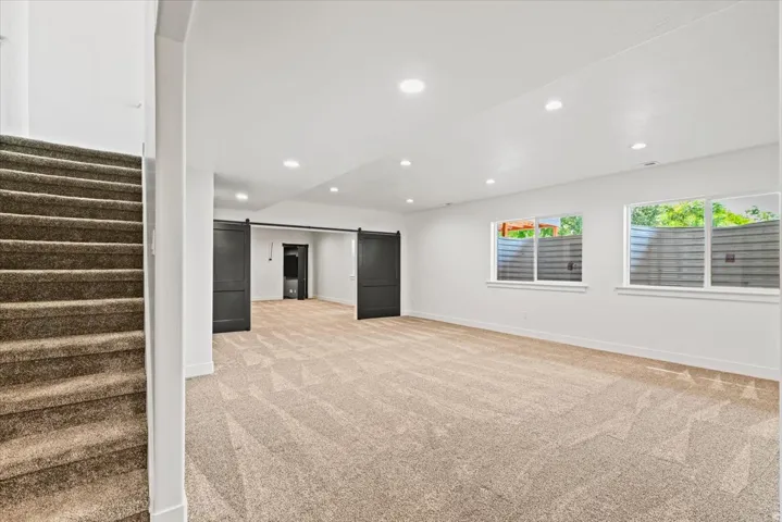 Spacious open floor plan with plush carpet flooring, recessed ceiling lighting, and abundant natural light from multiple windows
