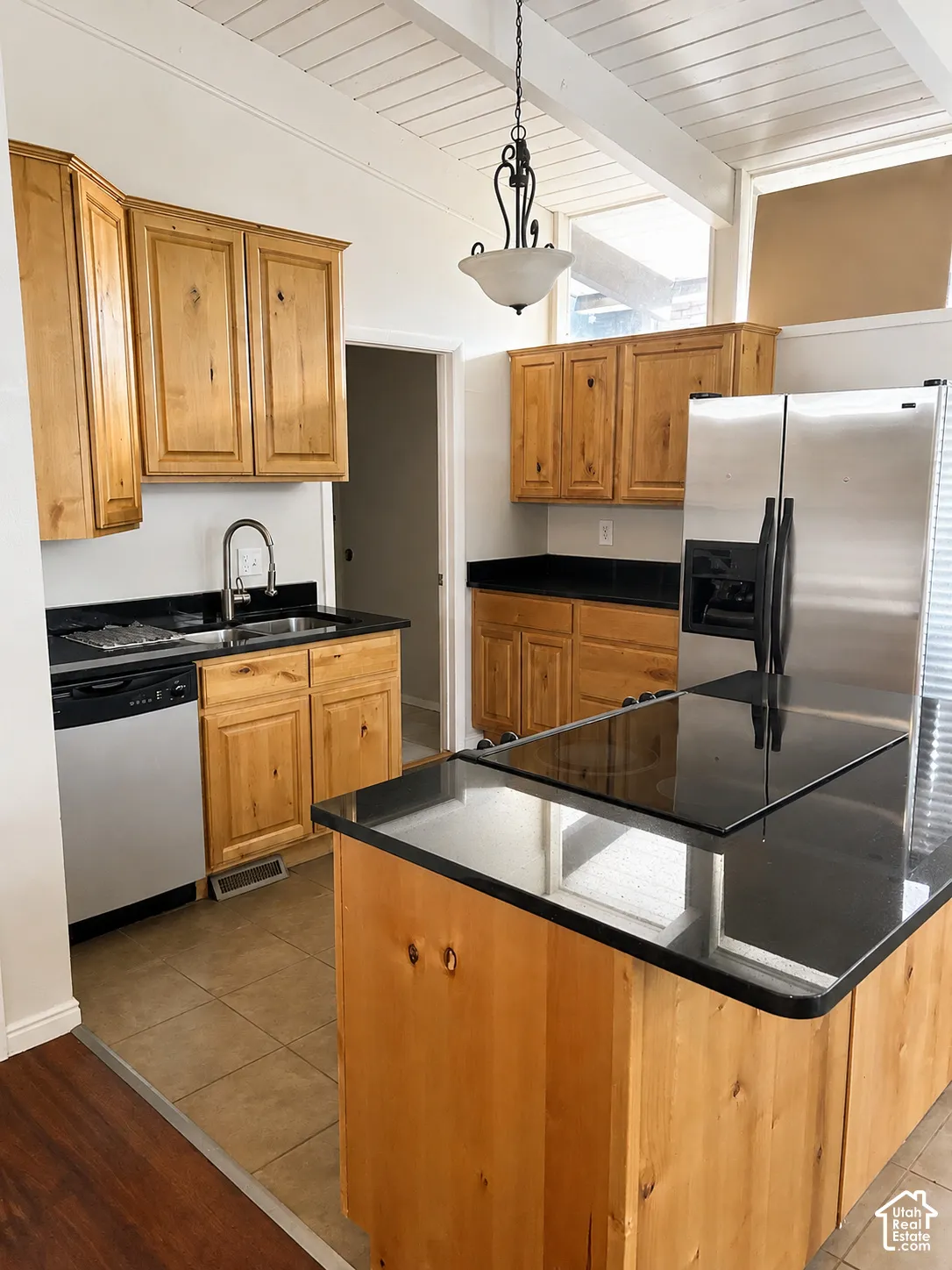Kitchen featuring wood cabinetry, dark countertops, stainless steel appliances, and tile flooring