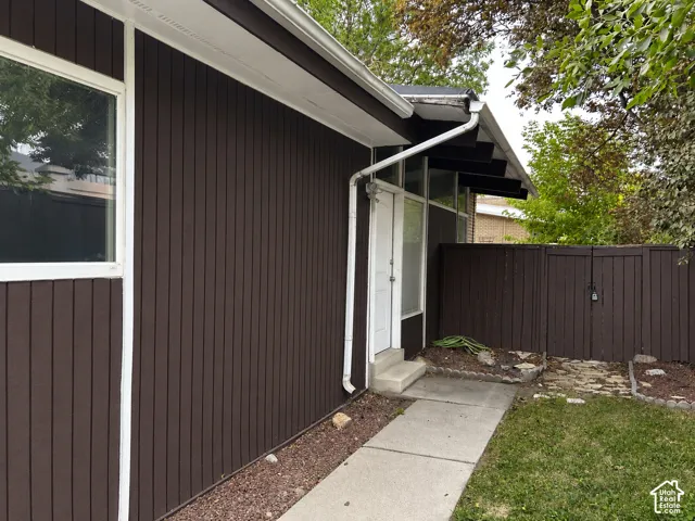 Vertical siding exterior with white window trim and a concrete walkway