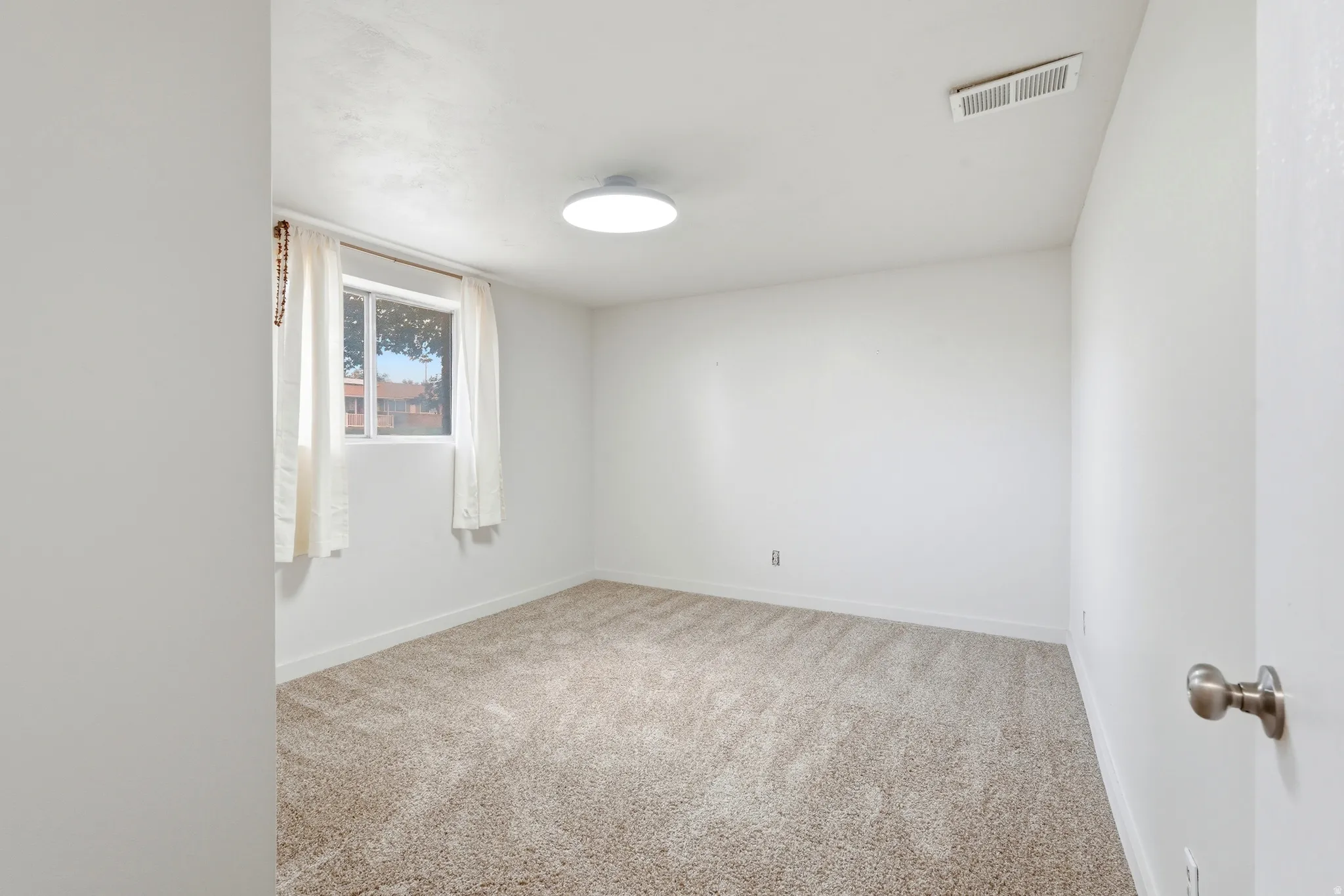 Neutral-toned carpeting extends throughout this room, complemented by white walls and a white ceiling