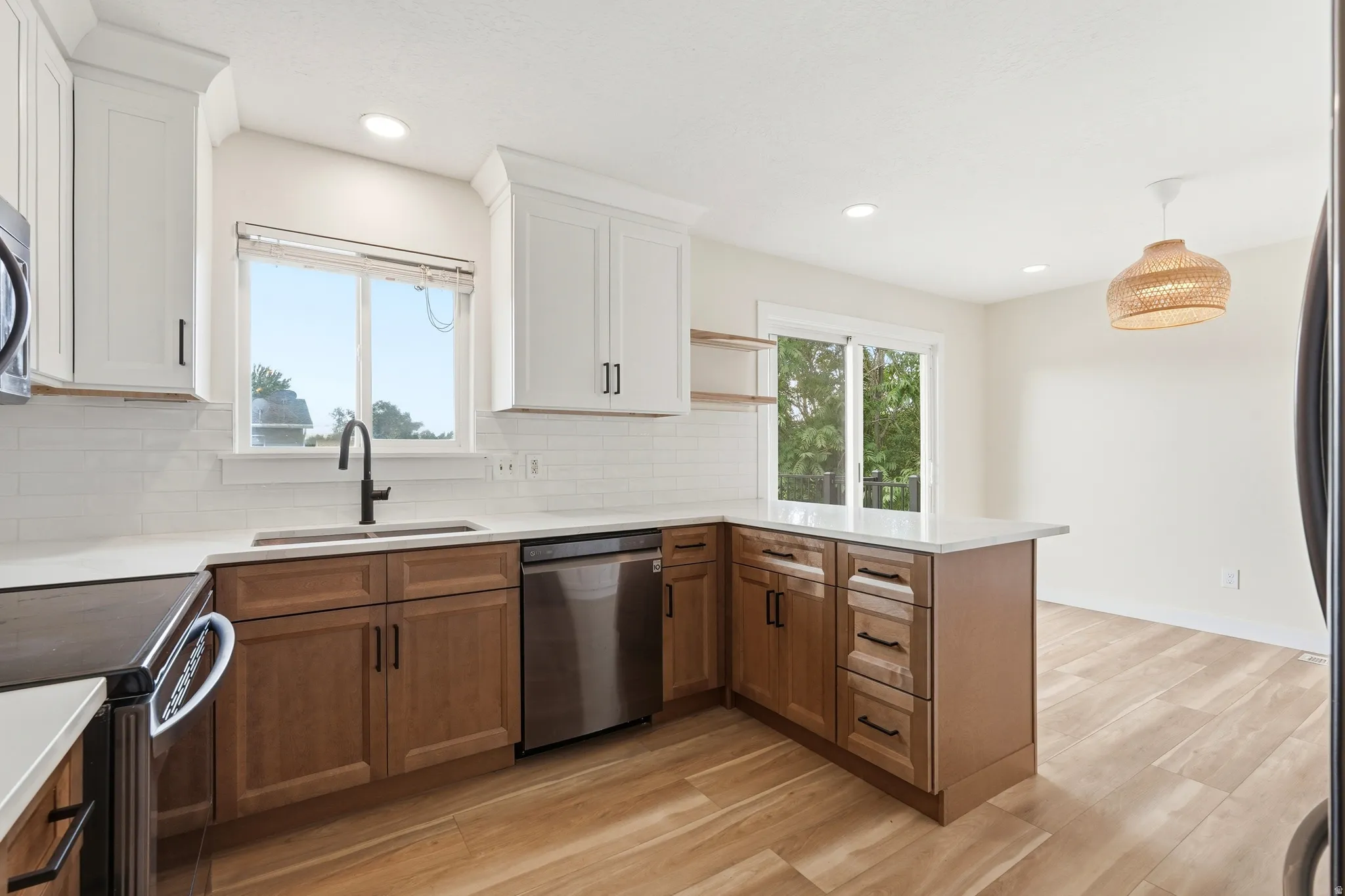 Contemporary kitchen featuring two-tone cabinetry, white countertops, a subway tile backsplash, and stainless steel appliances