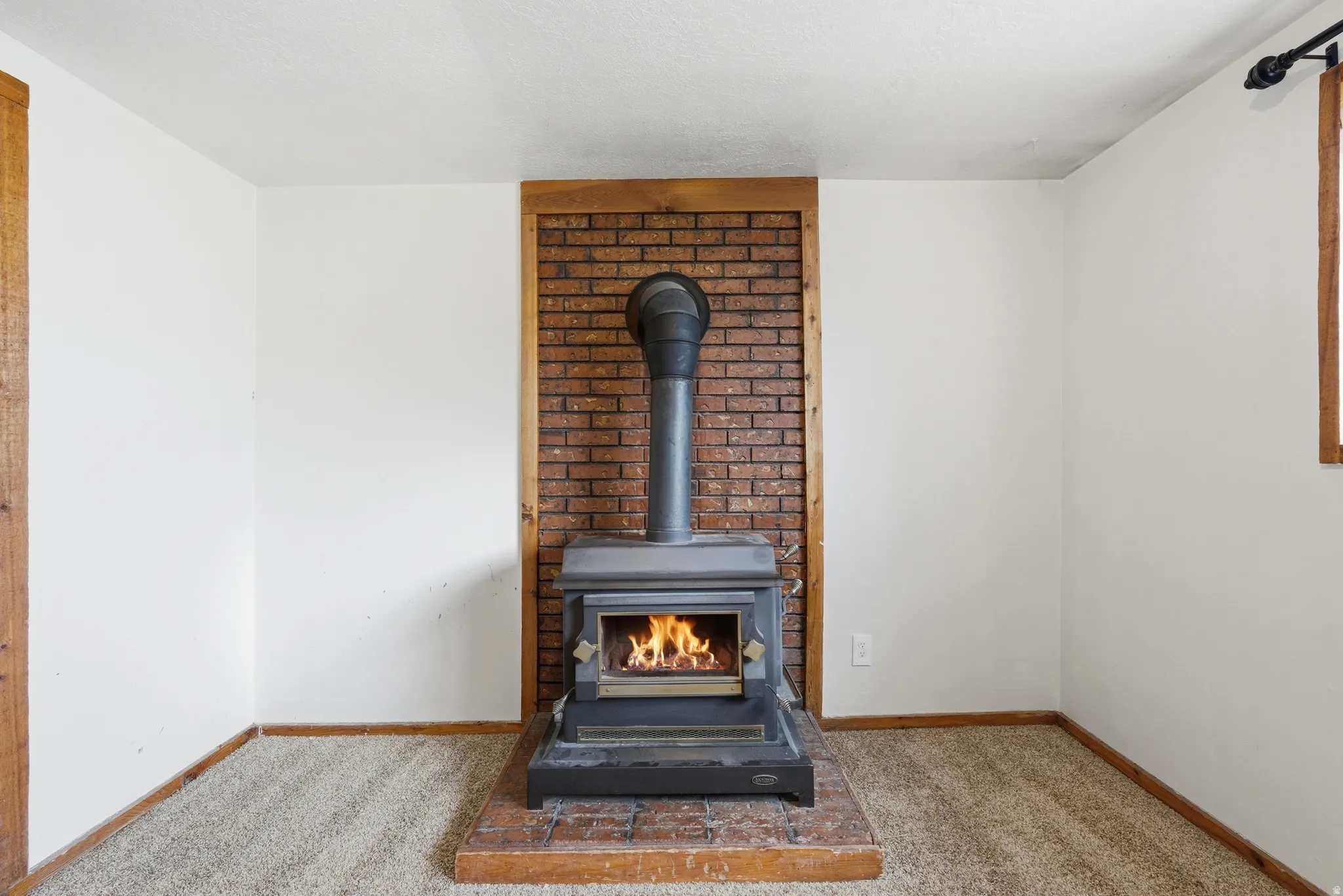 Wood-burning stove set against a brick accent wall with wood trim, featuring a brick hearth
